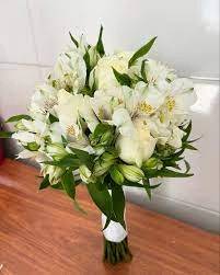 Arranjo de flores brancas composto por rosas e lírios, ideal para ocasiões especiais como casamentos, funerais ou celebrações de paz e pureza.
