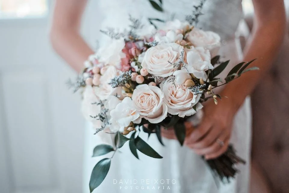 Bouquet de casamento com rosas brancas, folhagens e detalhes em rosa claro, ideal para decoração de bodas ou cerimônias especiais.
