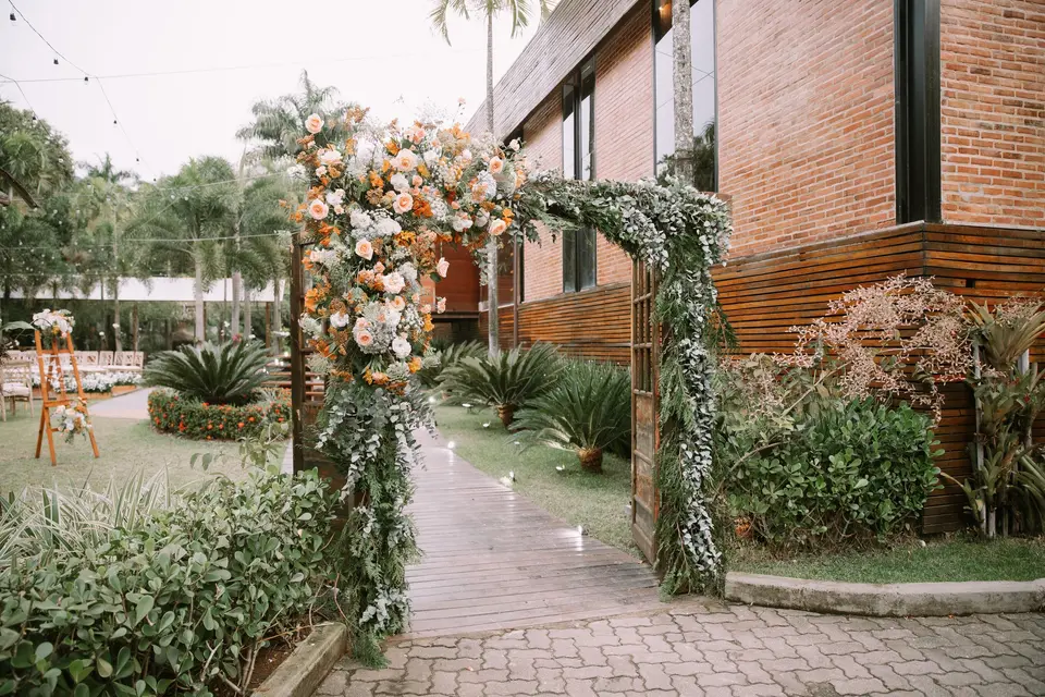 Decoração de casamento ao ar livre com arco de flores e jardim bem cuidado