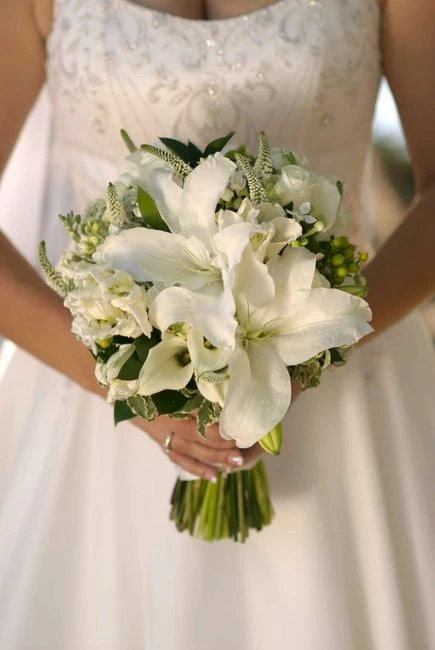 Buquê de casamento com flores brancas, incluindo lírios e outras flores delicadas, ideal para ocasiões especiais como casamentos.