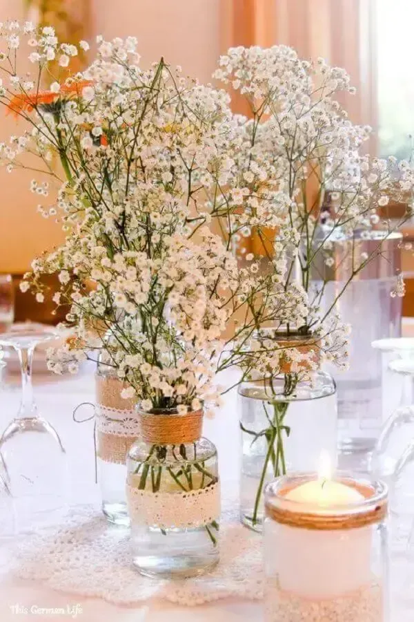 Arranjo de flores de bebé's breath em vidros de vidro decorativos em uma mesa, ideal para decoração delicada em eventos e ocasiões especiais.
