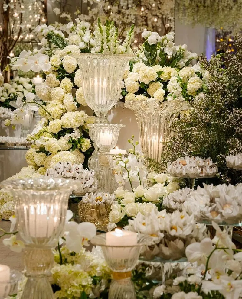Decoração elegante de casamento com arranjos de flores brancas, velas e vasos de cristal para criar uma atmosfera romântica e sofisticada.