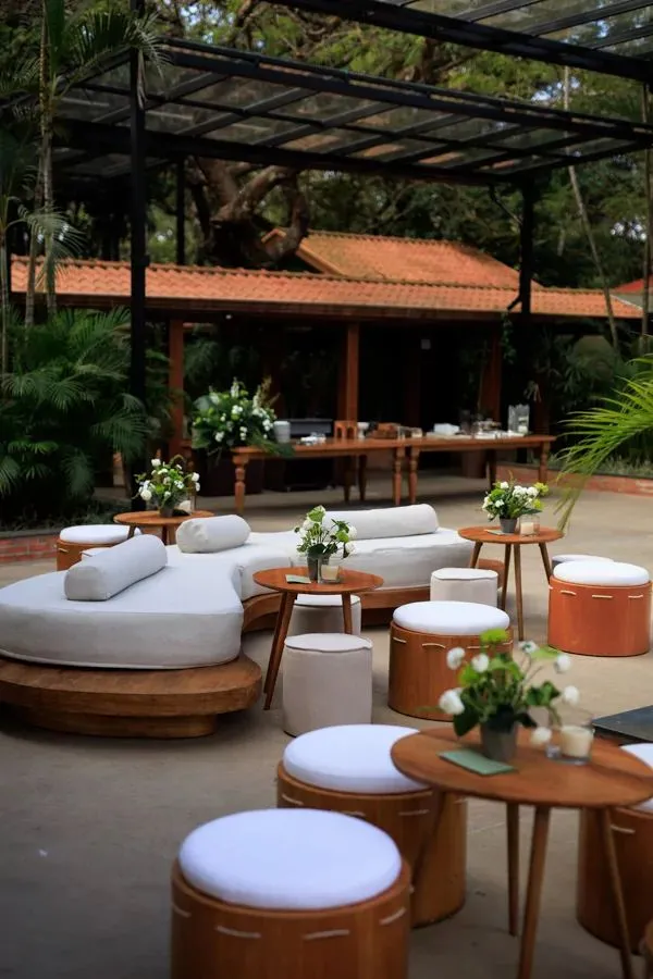 Decoração de varanda ao ar livre com móveis de crochê brancos e banquetas de madeira, ideal para eventos elegantes ao ar livre.
