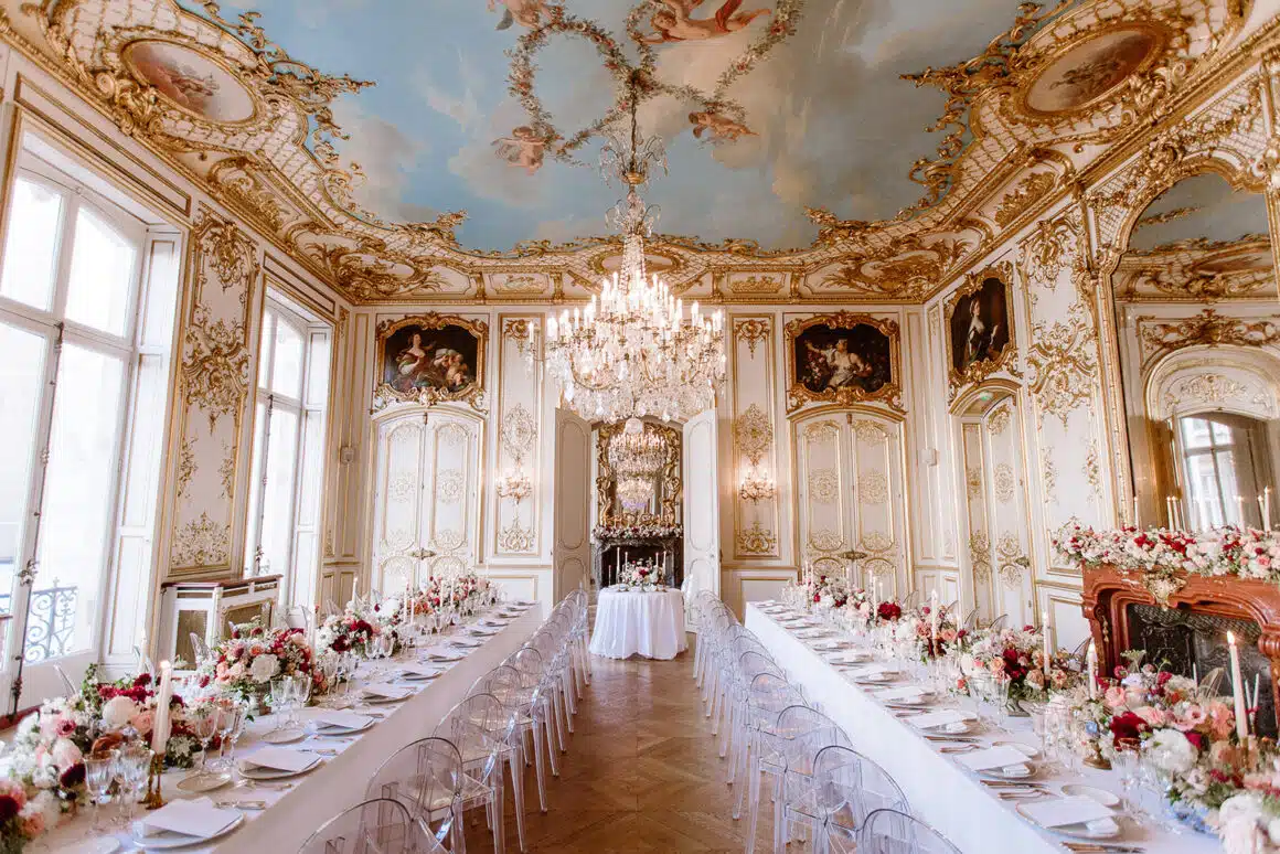 Salão de festa decorado com detalhes dourados, teto pintado e iluminação luxuosa, ideal para eventos elegantes e celebrações sofisticadas.