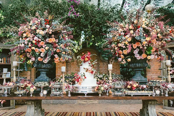 Decoração de casamento com arranjos de flores coloridas e bolo centralizado, ideal para eventos especiais ao ar livre.