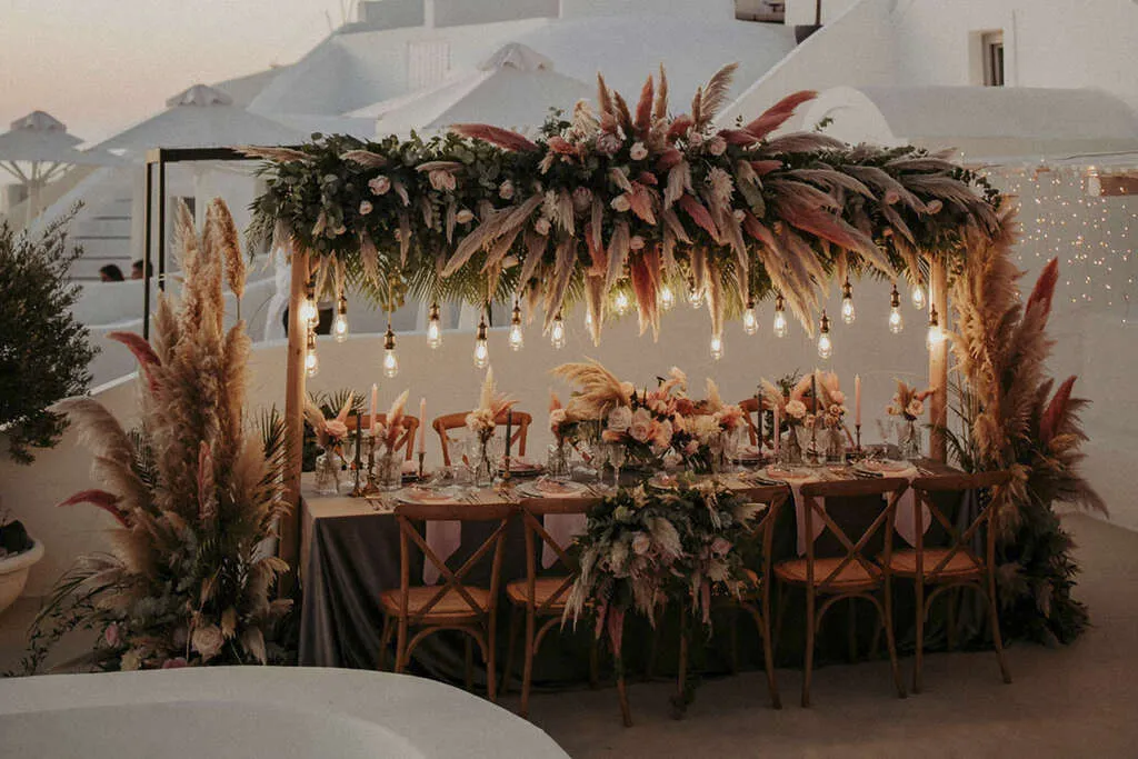 Decoração de casamento ao ar livre com mesa elegante, arranjos florais sofisticados, iluminação suave e ambiente romântico em estilo boho chic.