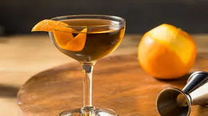 Imagem de um coquetel elegante em uma taça de vidro, decorado com uma fatia de laranja, ao lado de uma laranja e um saca-rolhas, ideal para festas e eventos especiais.