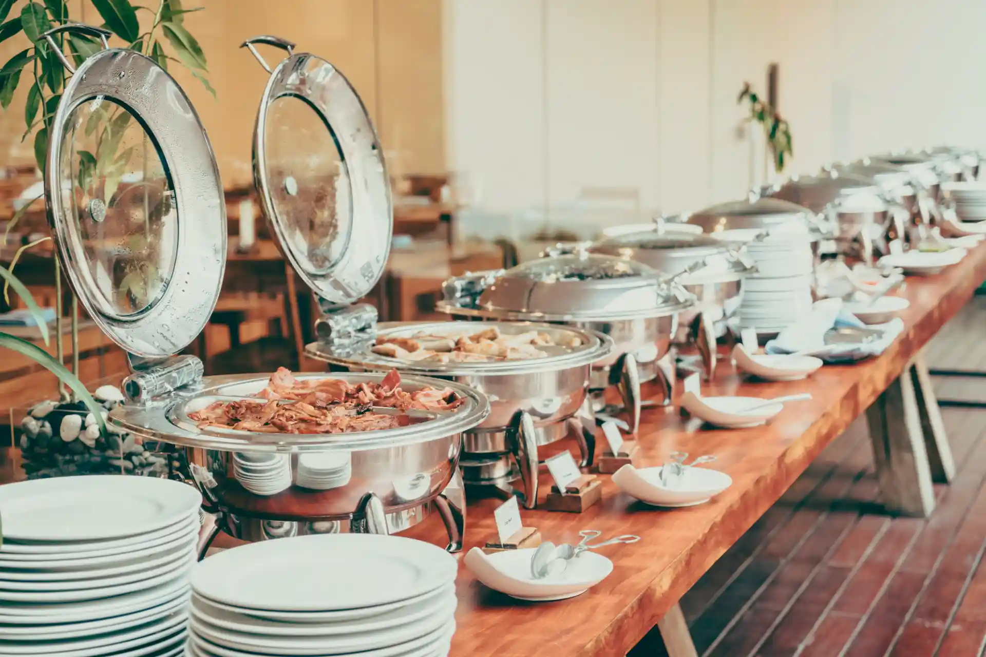 Buffet de café da manhã com diversas opções de alimentos servidos em pratos de inox, incluindo ovos e pães, ideal para eventos ou hospedagens.