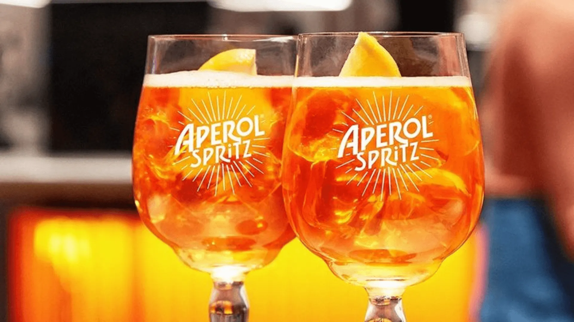 Duas taças de Aperol Spritz com gelo e fatias de limão, apresentando uma bebida refrescante e vibrante ideal para momentos de lazer e convívio social.