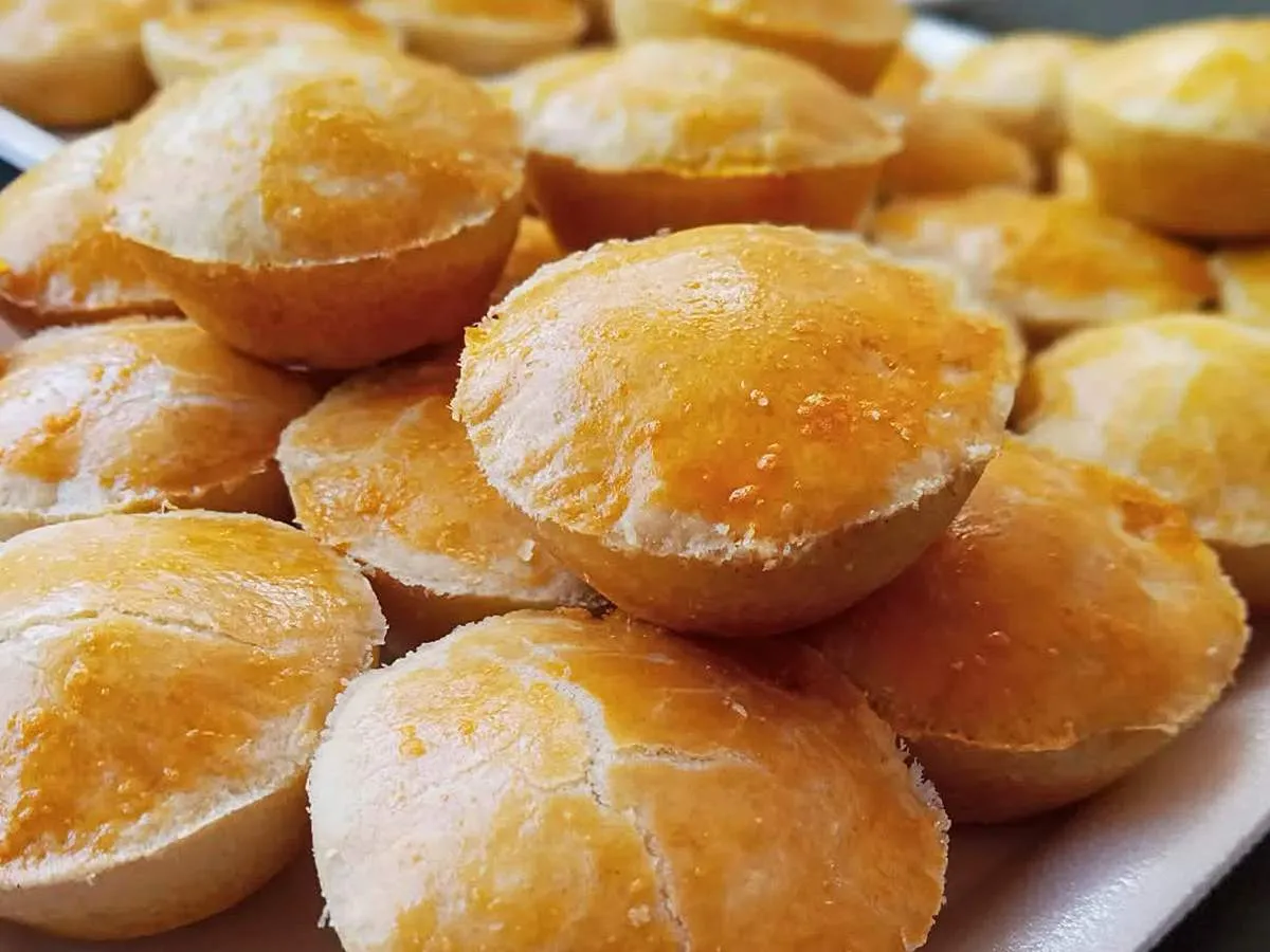Close-up de empadas de queijo douradas e crocantes em uma bandeja, perfeitas para lanche ou festa.