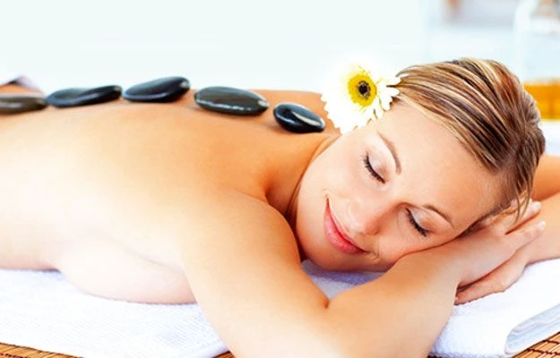Imagem de mulher recebendo uma sessão de terapia com pedras quentes nas costas, aproveitando a sensação de relaxamento. Ideal para quem busca bem-estar e tratamentos de spa.