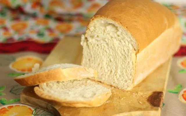 Pão de forma caseiro com crosta dourada e interior macio, ideal para sanduíches, café da manhã ou lanche, posicionado sobre uma tábua de madeira.