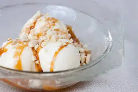 Sobremesa de sorvete de banana com calda de caramelo em tigela de vidro, ideal para sobremesas ou lanches doces.