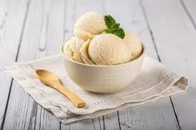 Sorvete de coco artesanal em tigela de porcelana branca, decorado com hortelã fresca, servido com colher de madeira em ambiente clean e aconchegante.