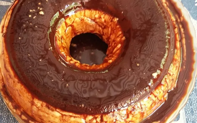 Imagem de um bolo de chocolate com cobertura de ganache formando um buraco no centro, decorado com detalhes de chocolate ao redor. Perfeito para ocasiões especiais.