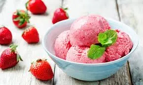 Sorbet de morango caseiro em uma tigela azul, servido com folhas de hortelã, rodeado de morangos frescos e criando uma sobremesa refrescante e deliciosa.