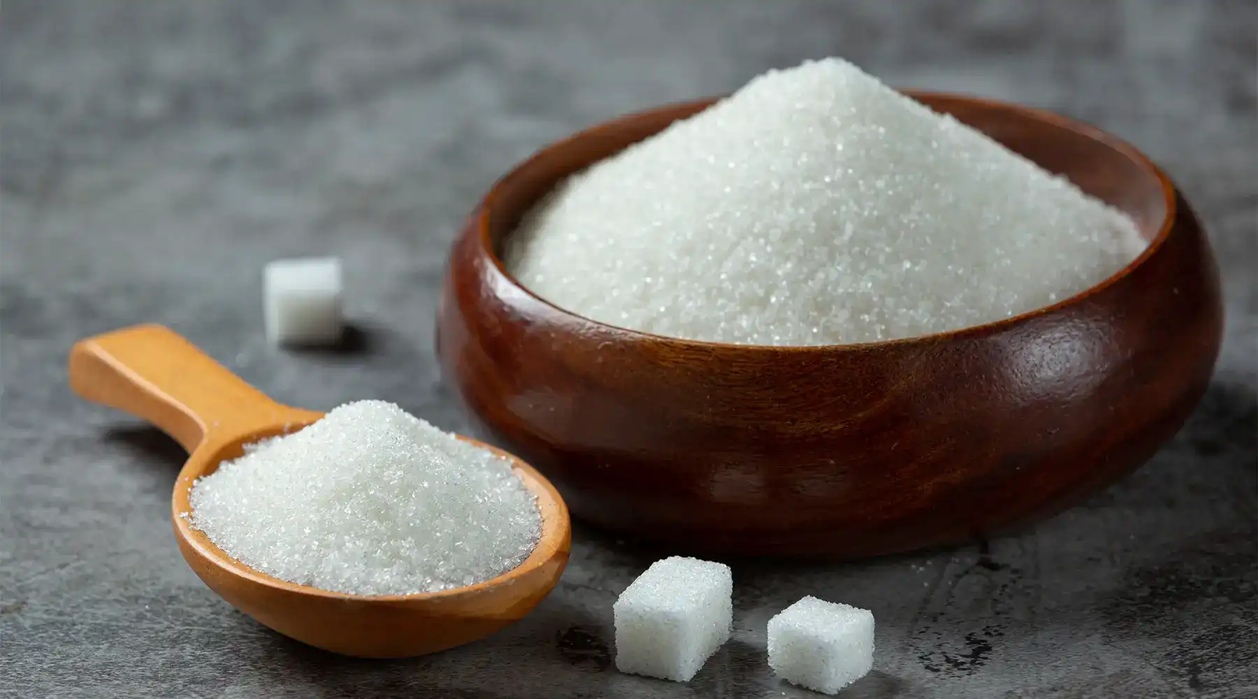 Adoçante culinário em prato de madeira e colher de madeira, usada na culinária para adoçar o sabor dos alimentos.