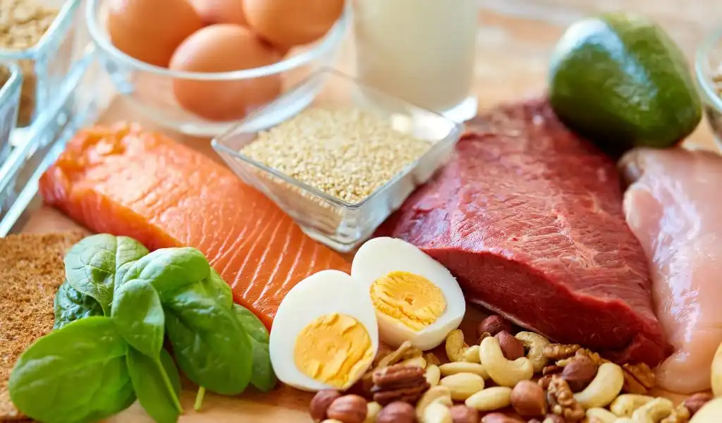 Seleção de alimentos ricos em proteínas e ricos em nutrientes, incluindo ovos, carne, peixe, castanhas, legumes e verduras, ideal para uma dieta saudável.