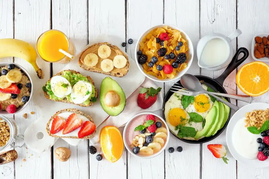 Variedade de cafés da manhã saudáveis e nutritivos, incluindo ovos, frutas, sucos naturais, aveia, pão integral com banana e avocado, ideal para uma rotina equilibrada.