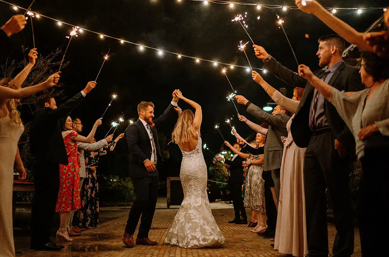 Casamento ao ar livre à noite com convidados segurando velas acesas, celebrando a união do casal em uma cerimônia emocionante e descontraída.