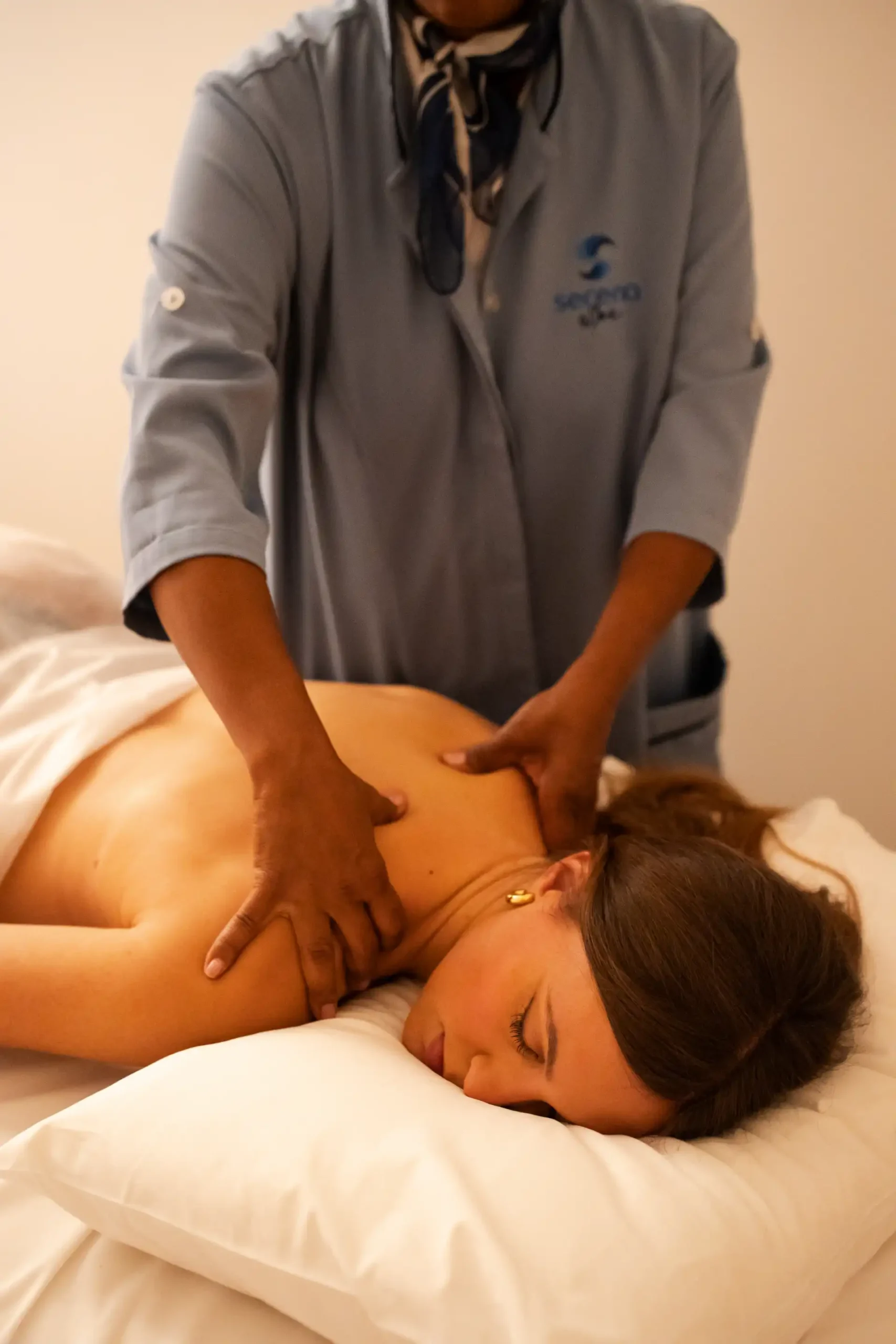 Sessão de massagem relaxante em mulher deitada de lado na cama. Masageiro masculino aplicando técnica de massagem terapêutica no corpo da cliente.