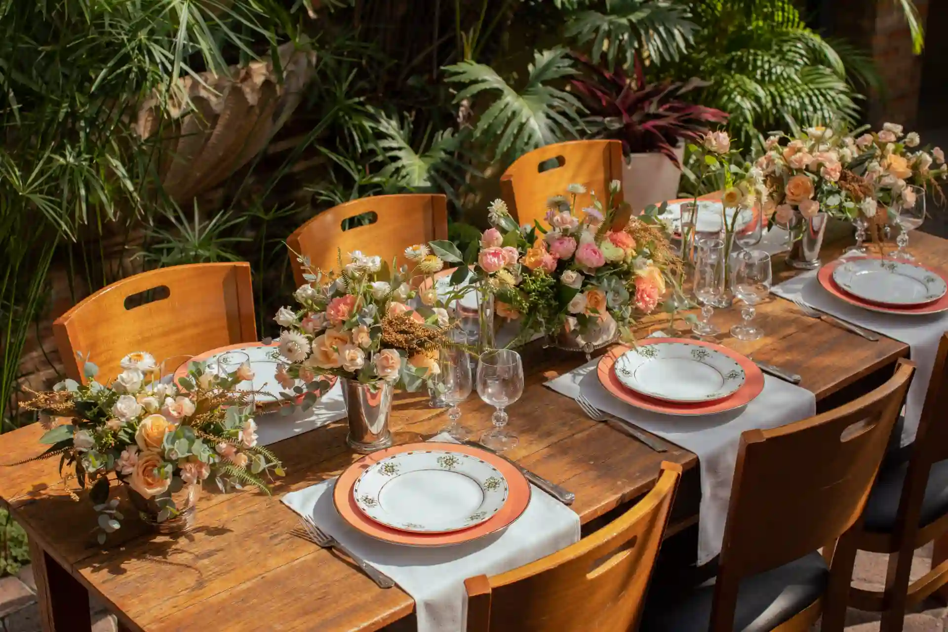 Mesa de jantar elegante decorada com arranjos de flores na primavera, pronta para um almoço ou jantar especial ao ar livre.