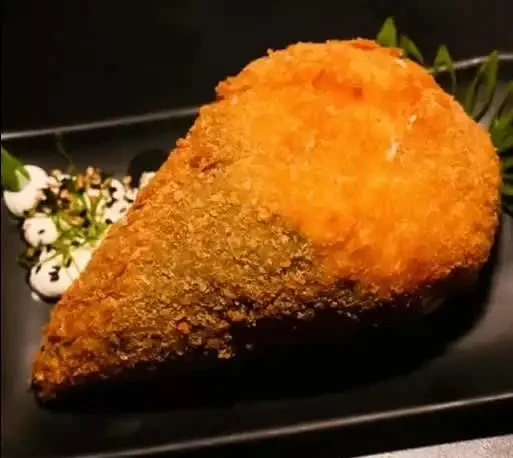 Imagem de um hot temaki com crosta dourada servido em um prato preto, destaque para sua textura crocante e recheio saboroso, ideal para petiscos.