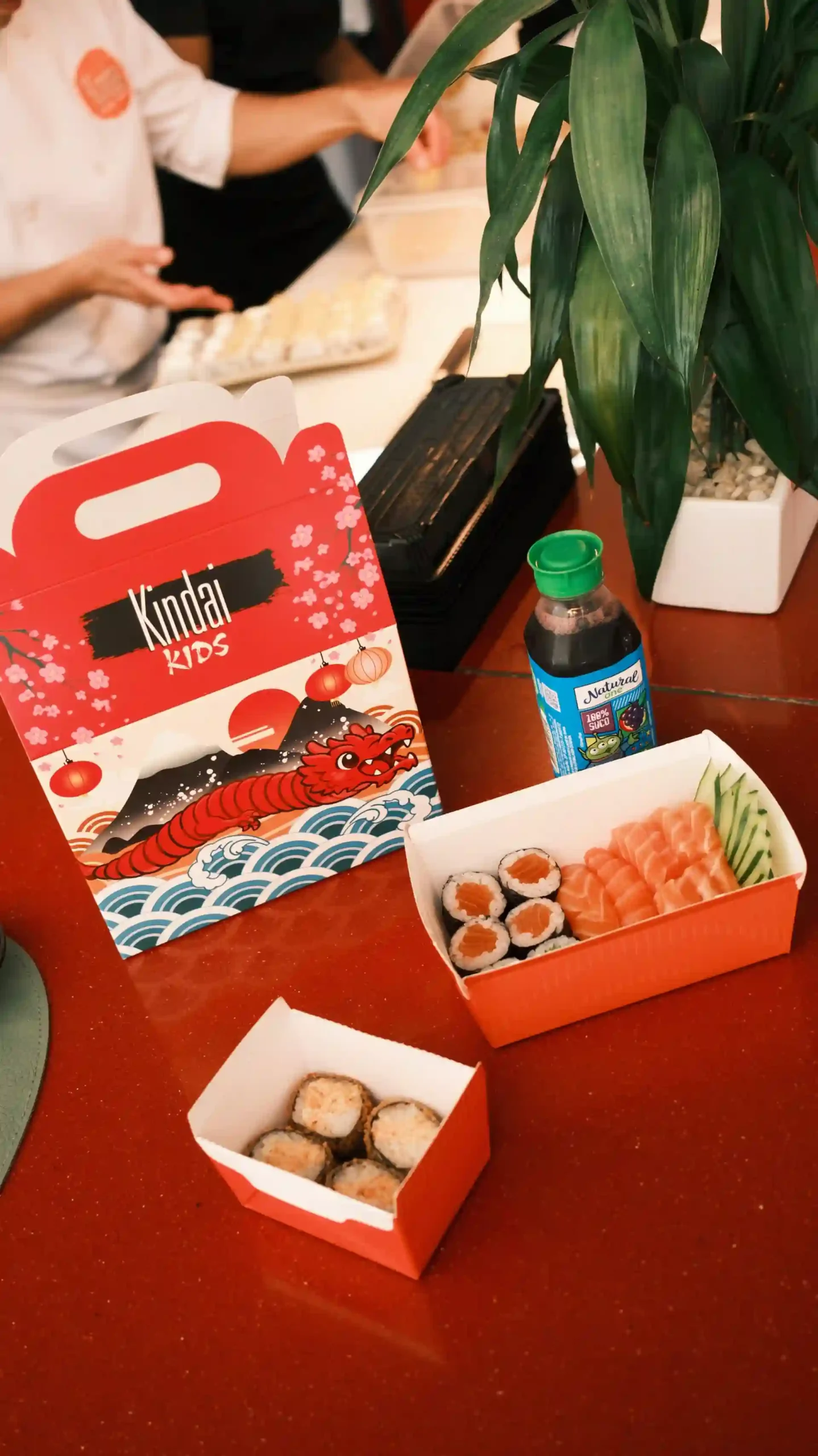 Kit de comida infantil para crianças com sushi, gengibre, molho e itens temáticos de dragão em embalagem colorida da marca Kindai Kids.