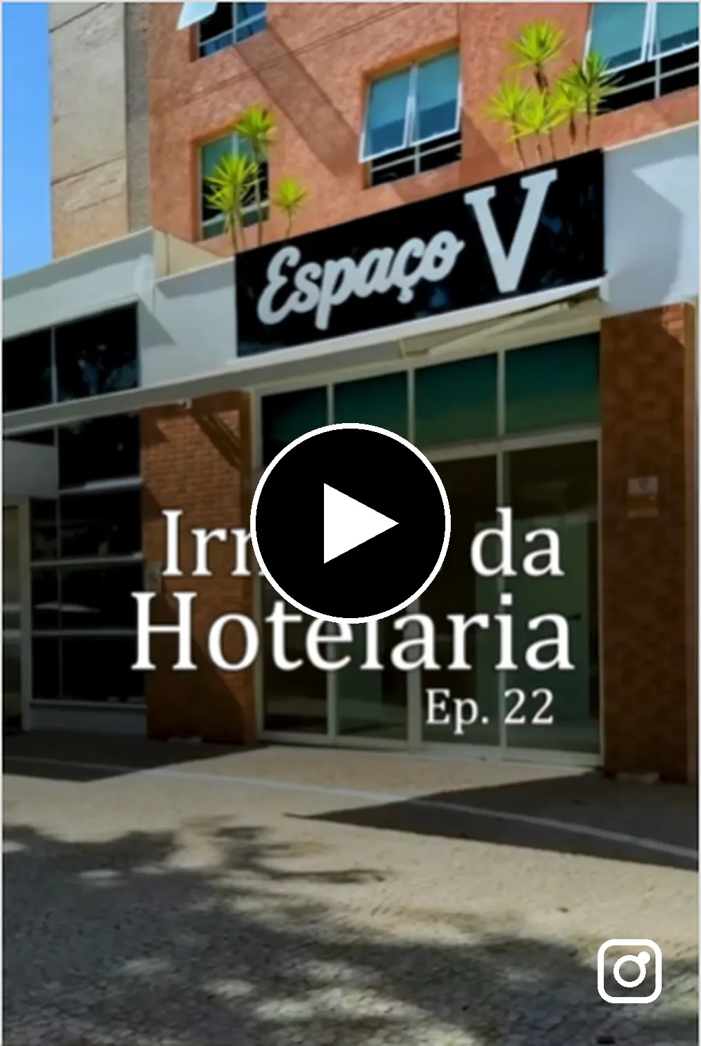 Prédio moderno com fachada de tijolos e varandas, banner escrito “Espaço V”