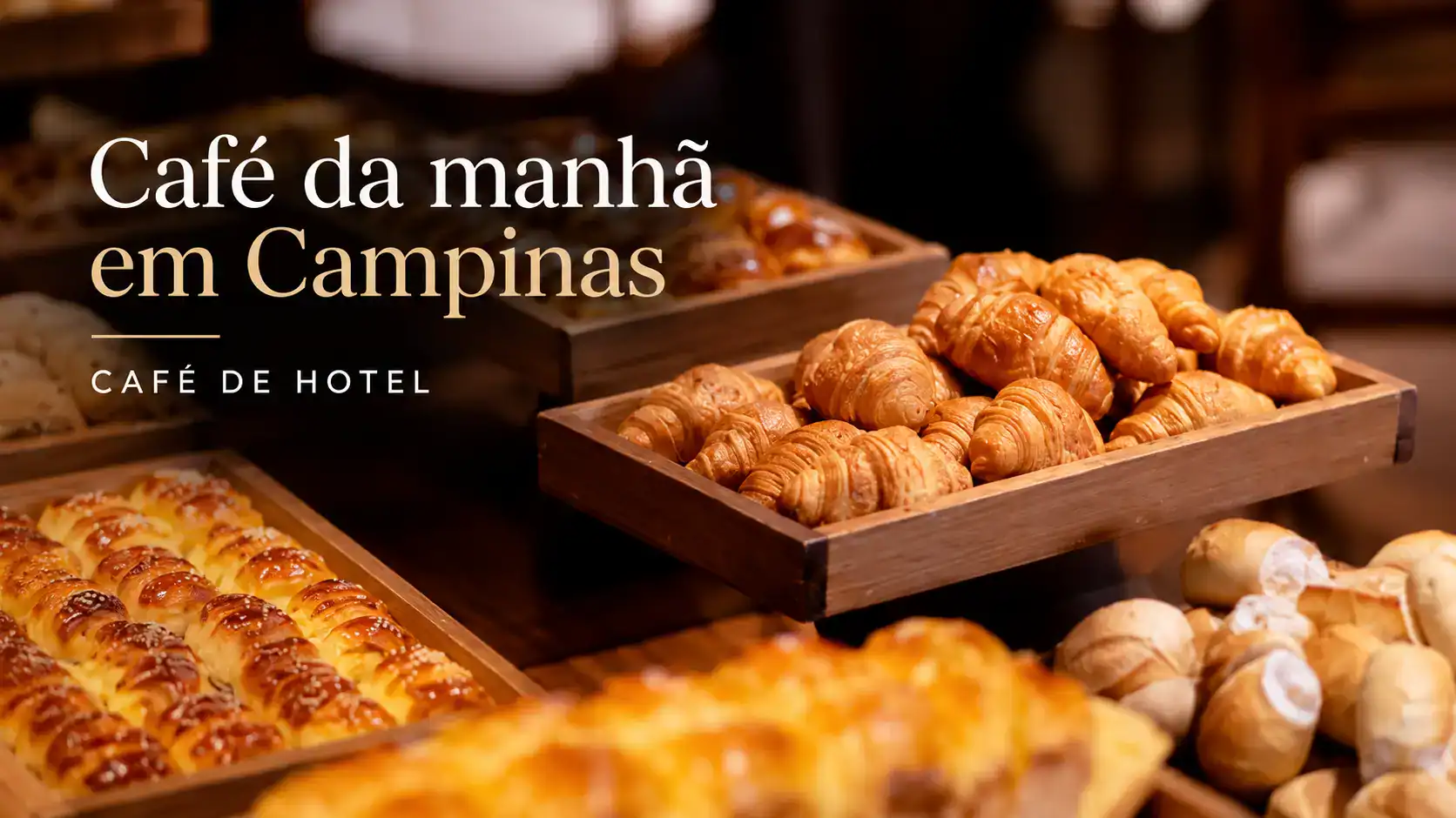 Café da manhã em Campinhas com bandejas de croissants e pães assados, incluindo croissants dourados em caixa de madeira e ambiente de hotel ao fundo.