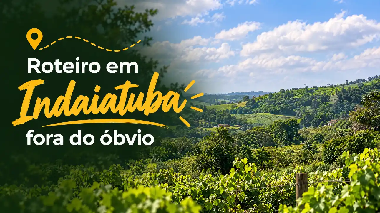 Paisagem rural com vinhedos ao longo de uma colina, céu azul com nuvens e texto promocional “Roteiro em Indaiatuba fora do óbvio” na imagem.